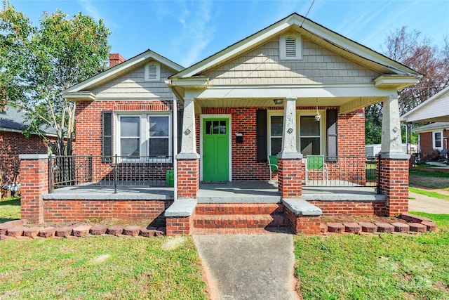 bungalow-style home with a porch, a front lawn, and brick siding