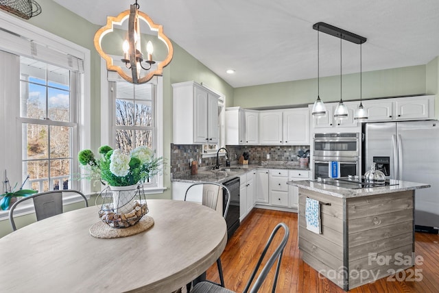 kitchen with a sink, backsplash, black appliances, and light stone countertops