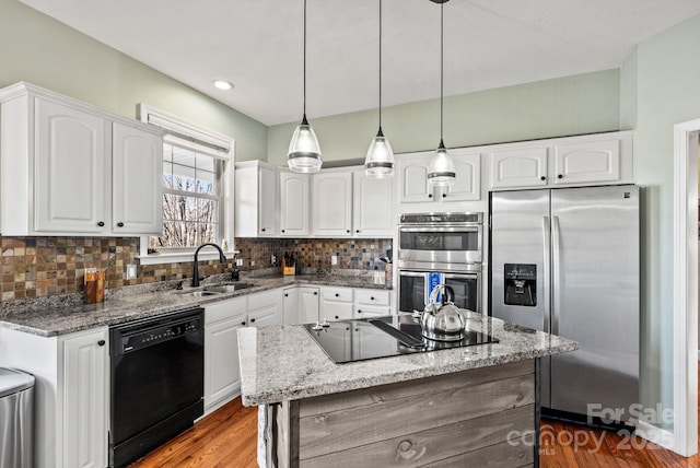 kitchen featuring tasteful backsplash, light stone countertops, black appliances, white cabinetry, and a sink