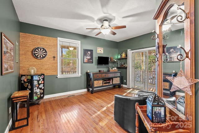 interior space featuring visible vents, ceiling fan, a textured ceiling, baseboards, and hardwood / wood-style flooring