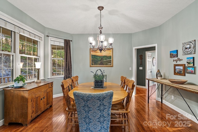 dining space featuring baseboards, a notable chandelier, and hardwood / wood-style floors