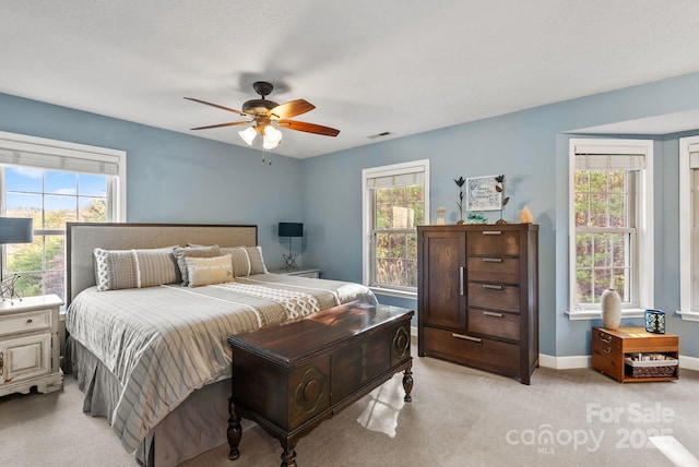 bedroom with a ceiling fan, light colored carpet, visible vents, and baseboards