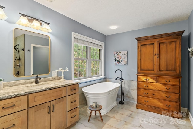 bathroom featuring a textured ceiling, walk in shower, a freestanding bath, and vanity