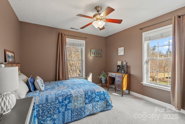 carpeted bedroom featuring baseboards, a textured ceiling, visible vents, and a ceiling fan