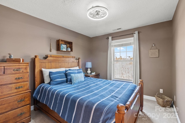 bedroom featuring light carpet, visible vents, baseboards, and a textured ceiling