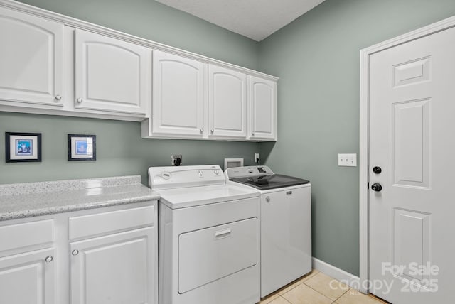 washroom featuring cabinet space, light tile patterned floors, baseboards, a textured ceiling, and washing machine and dryer