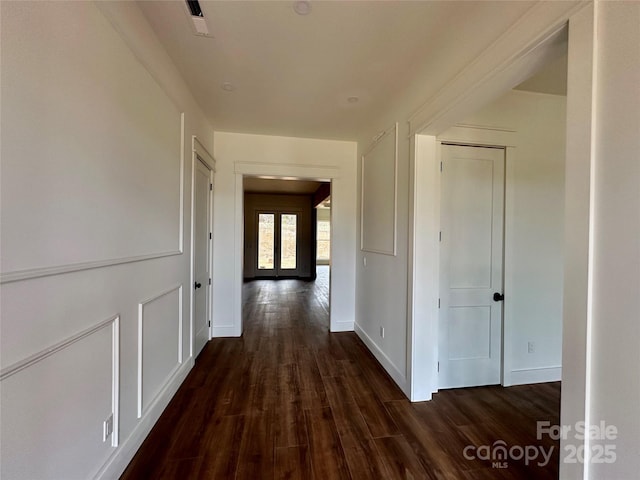 hallway featuring dark wood-style floors, baseboards, visible vents, and french doors