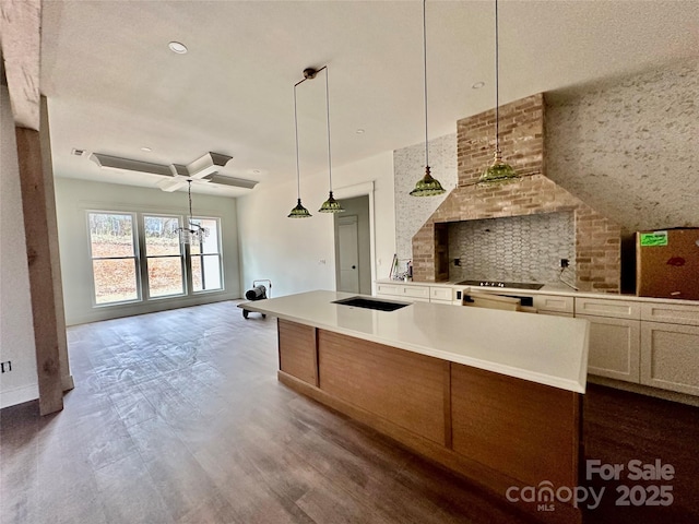 kitchen featuring tasteful backsplash, pendant lighting, light countertops, and a center island with sink