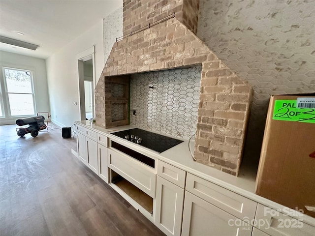 kitchen featuring tasteful backsplash, white cabinets, dark wood-style floors, light countertops, and black electric cooktop