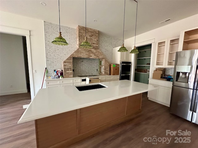 kitchen with light countertops, visible vents, white cabinets, a sink, and stainless steel fridge