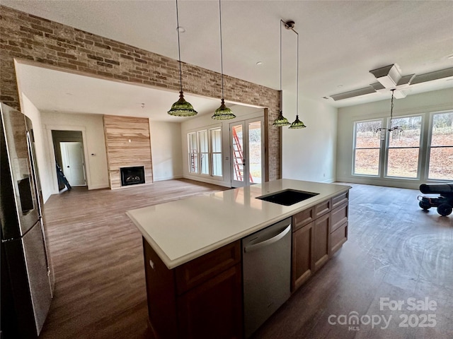 kitchen with stainless steel appliances, light countertops, open floor plan, brick wall, and a tile fireplace