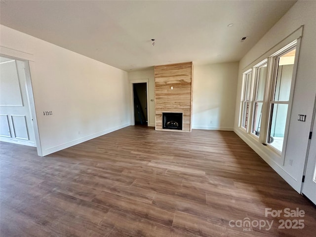 unfurnished living room with visible vents, a fireplace, baseboards, and wood finished floors