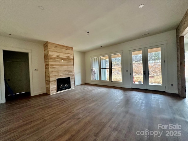 unfurnished living room with a premium fireplace, baseboards, dark wood-style flooring, and french doors