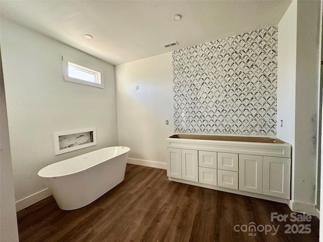 full bathroom featuring a freestanding bath, wood finished floors, visible vents, and baseboards