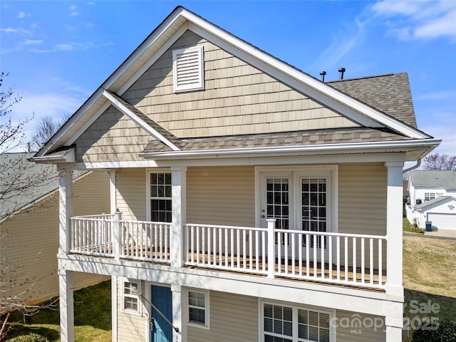 rear view of property with a shingled roof and a porch