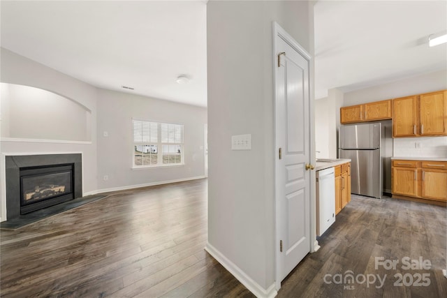 kitchen featuring a glass covered fireplace, dark wood-style floors, freestanding refrigerator, white dishwasher, and light countertops