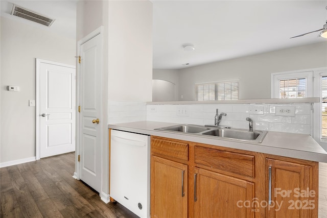 kitchen featuring white dishwasher, a sink, visible vents, and a healthy amount of sunlight