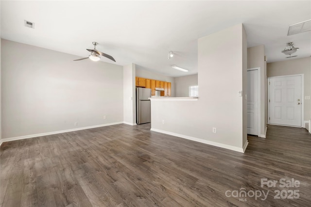 unfurnished living room featuring ceiling fan, dark wood-type flooring, visible vents, and baseboards