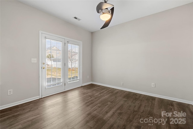 spare room featuring ceiling fan, dark wood-type flooring, visible vents, and baseboards