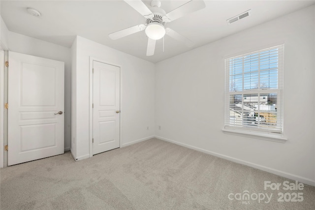 unfurnished bedroom featuring carpet floors, baseboards, visible vents, and a ceiling fan