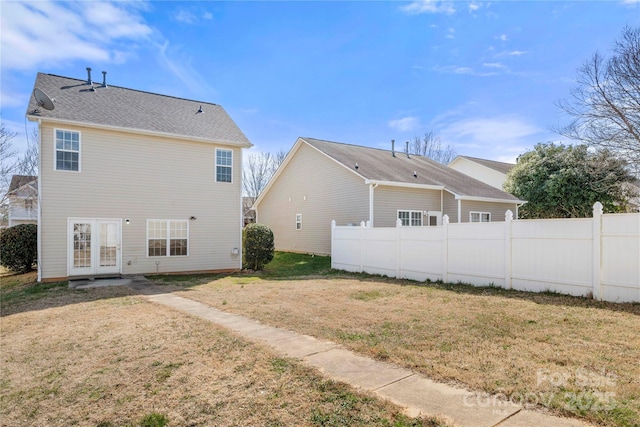 rear view of house featuring a yard, french doors, and fence