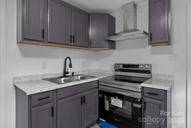 kitchen with light countertops, a sink, electric range, and wall chimney exhaust hood