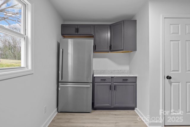 kitchen featuring freestanding refrigerator, light wood finished floors, and gray cabinetry