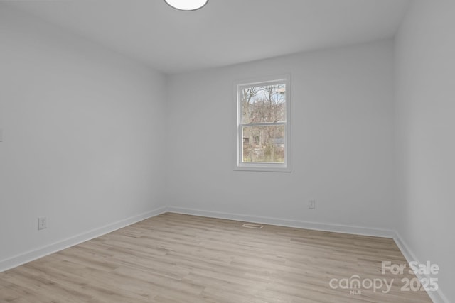 empty room with visible vents, light wood-style flooring, and baseboards