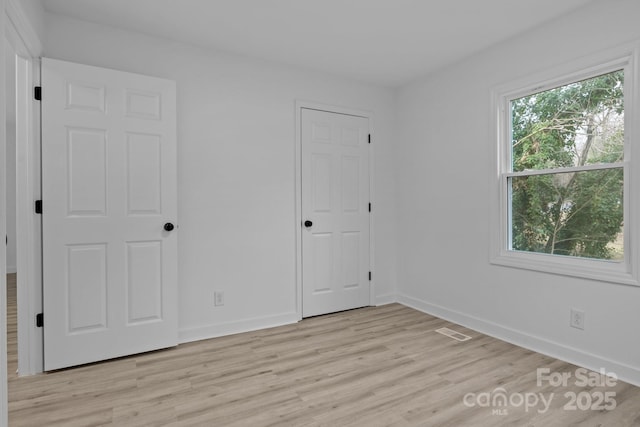 unfurnished bedroom featuring light wood finished floors, visible vents, and baseboards