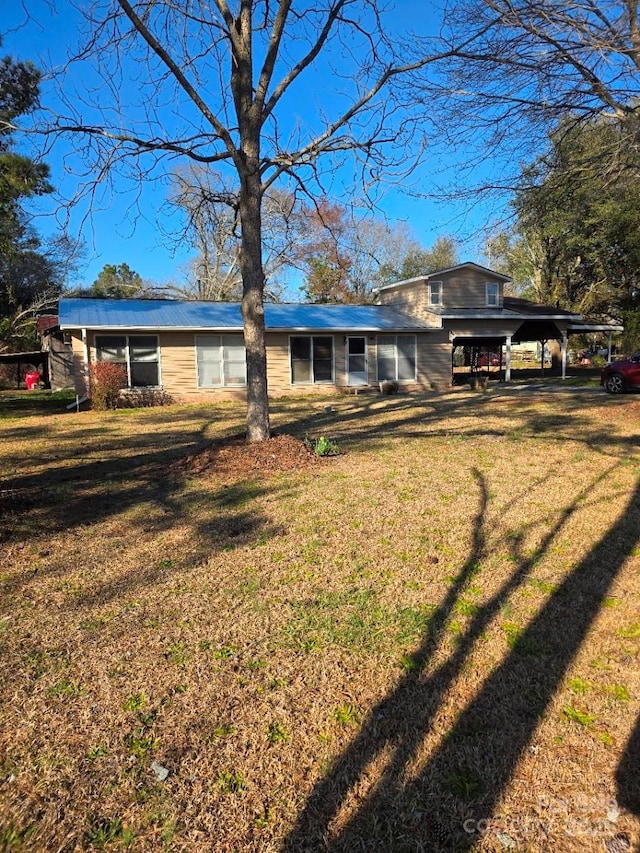 rear view of house featuring a yard and a carport