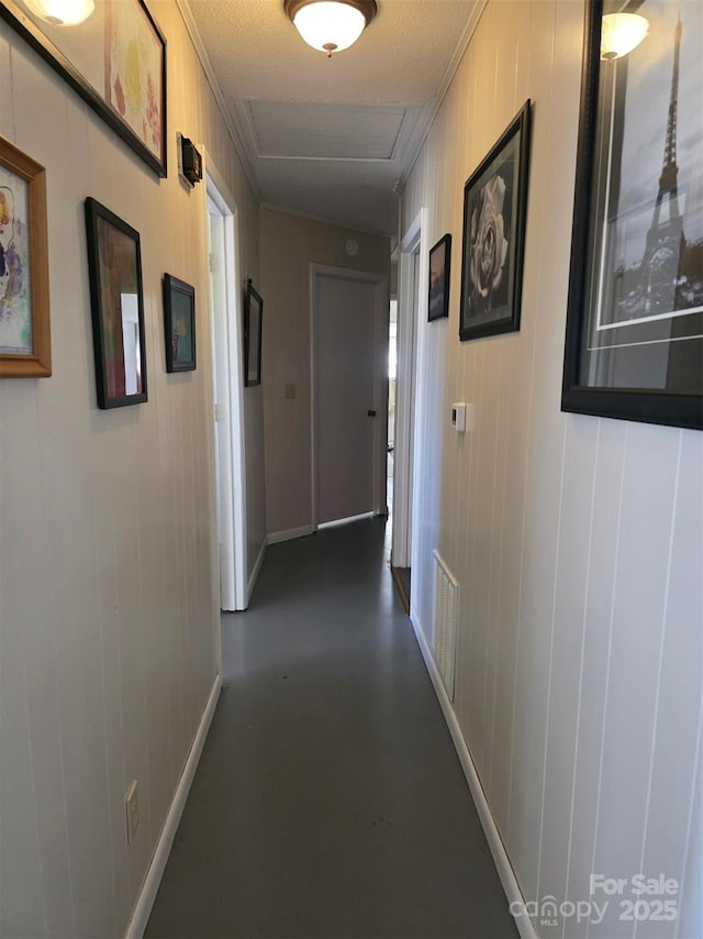 hall featuring visible vents, concrete floors, and baseboards