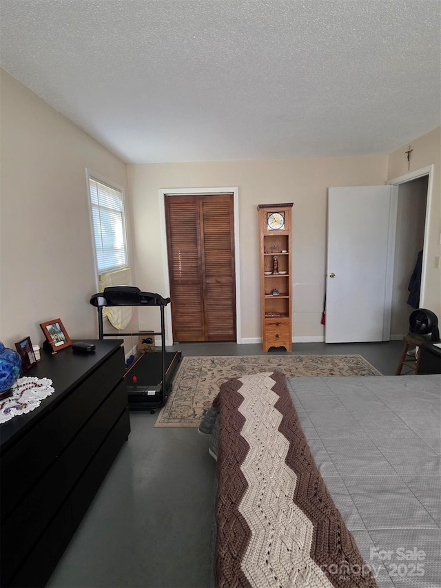 bedroom with a closet, concrete floors, and a textured ceiling