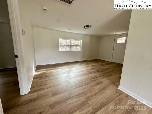 unfurnished room featuring baseboards, visible vents, and wood finished floors