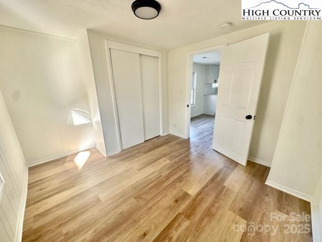 unfurnished bedroom with baseboards, a closet, and light wood-style floors