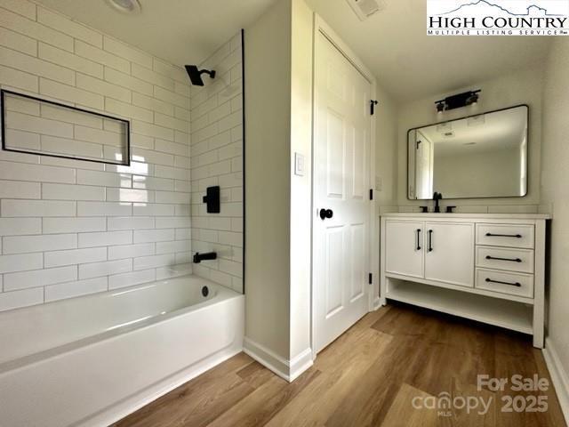 full bathroom featuring shower / bathing tub combination, wood finished floors, vanity, and baseboards