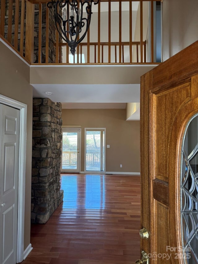 interior space featuring a notable chandelier, wood finished floors, a towering ceiling, and baseboards