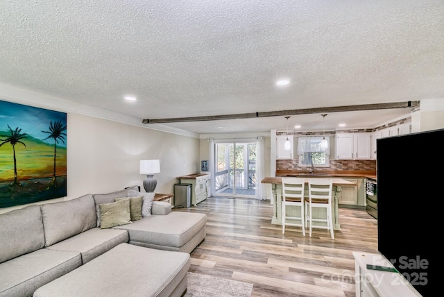 living room with light wood-style flooring, crown molding, a textured ceiling, and recessed lighting