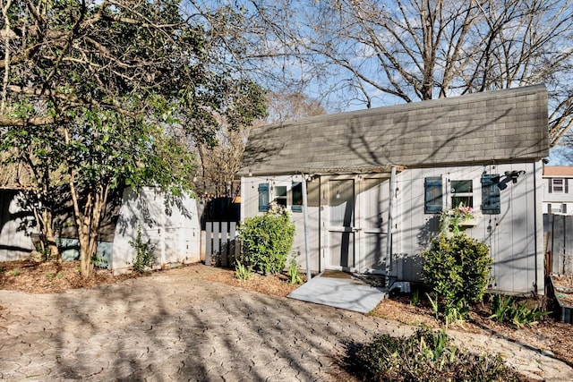 colonial inspired home with an outbuilding, roof with shingles, and fence