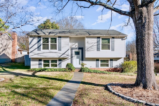 bi-level home featuring fence and a front lawn