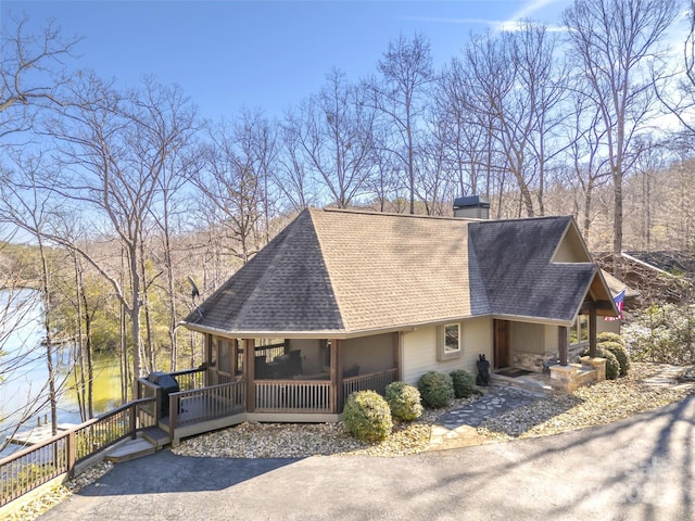 view of home's exterior with roof with shingles, a chimney, and a sunroom