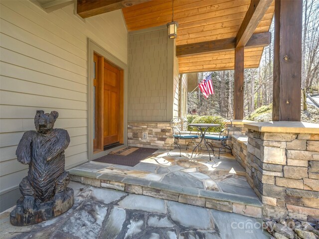 view of exterior entry with outdoor dining space and stone siding