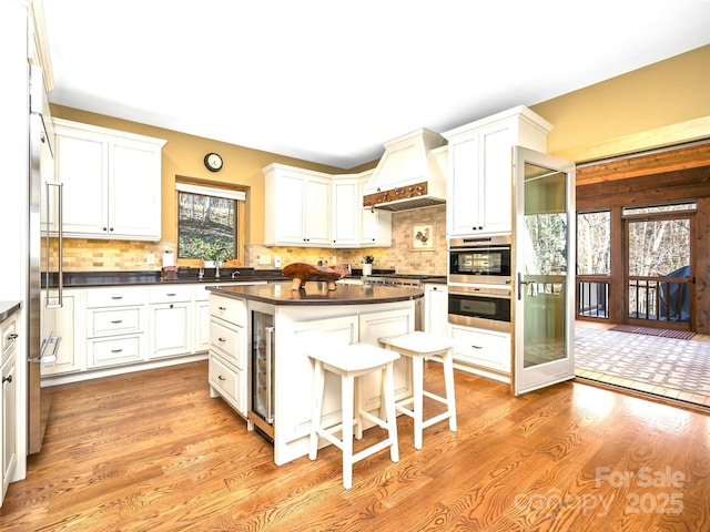 kitchen featuring dark countertops, custom range hood, a kitchen island, and white cabinets