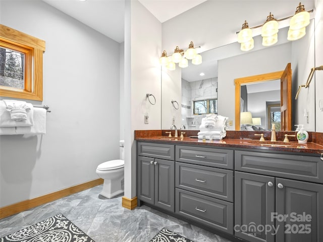 full bathroom featuring double vanity, a sink, toilet, and baseboards