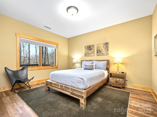 bedroom with wood finished floors, visible vents, and baseboards