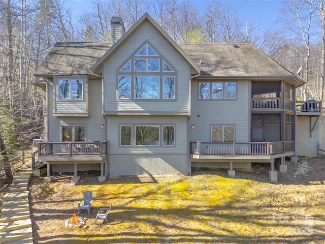 back of property with a yard, a chimney, a shingled roof, stairway, and a deck