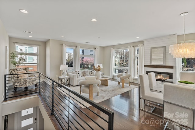 living room featuring a healthy amount of sunlight, visible vents, wood finished floors, and a glass covered fireplace