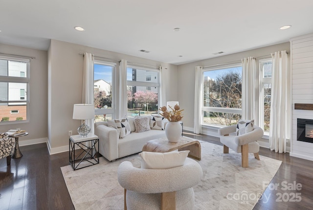 living room with wood finished floors, visible vents, and baseboards