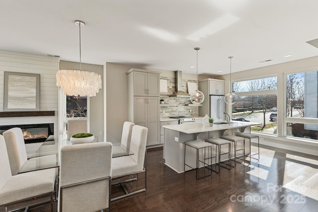 kitchen featuring a breakfast bar, light countertops, decorative backsplash, appliances with stainless steel finishes, and wall chimney exhaust hood