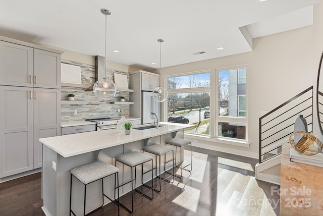 kitchen with visible vents, decorative backsplash, refrigerator, light countertops, and a sink