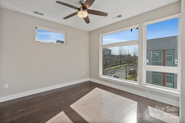 unfurnished room with a ceiling fan, dark wood-style flooring, visible vents, and baseboards